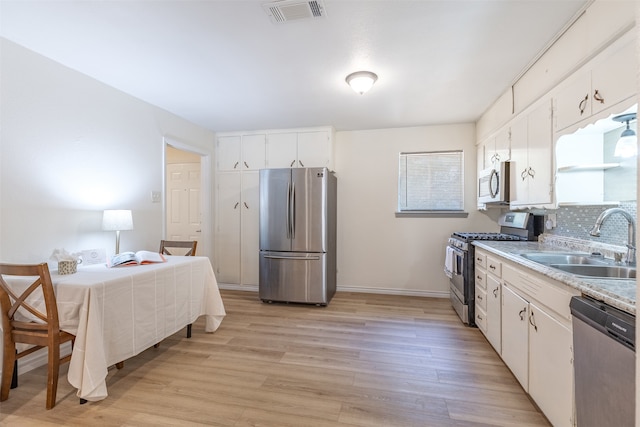 kitchen with light wood-type flooring, sink, stainless steel appliances, and white cabinets