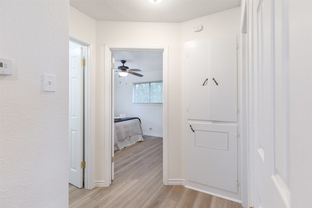 corridor featuring a textured ceiling and light hardwood / wood-style floors