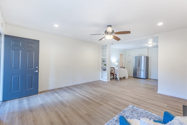 unfurnished living room featuring built in features, light wood-type flooring, and ceiling fan