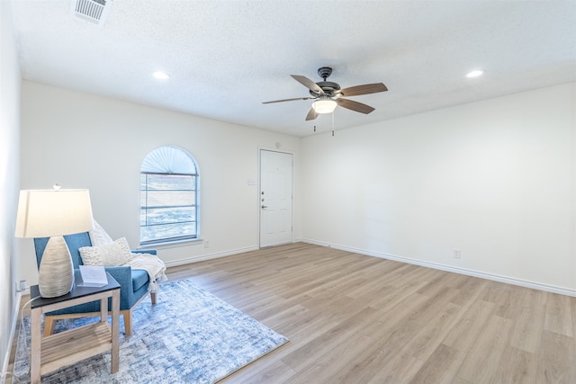 sitting room featuring light hardwood / wood-style floors, a textured ceiling, and ceiling fan