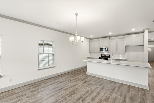 kitchen with white cabinets, appliances with stainless steel finishes, hanging light fixtures, and light hardwood / wood-style flooring