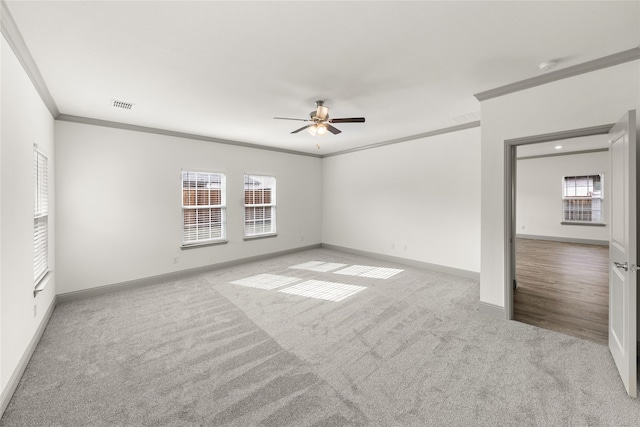 empty room featuring a healthy amount of sunlight, crown molding, light carpet, and ceiling fan