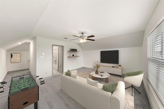 carpeted living room with ceiling fan and vaulted ceiling