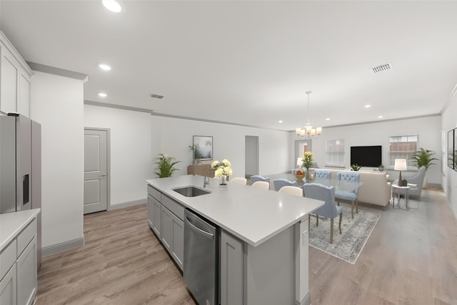 kitchen with light wood-type flooring, a center island with sink, a chandelier, and stainless steel appliances