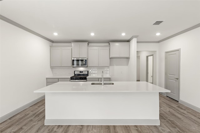 kitchen with a kitchen island with sink, stainless steel appliances, light wood-type flooring, and sink