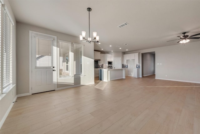 unfurnished living room featuring ceiling fan with notable chandelier and light hardwood / wood-style floors