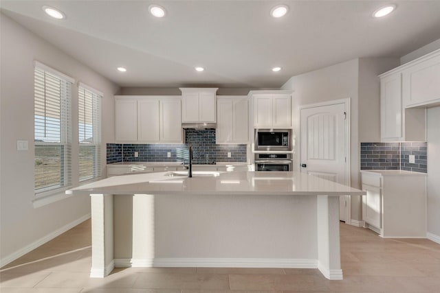 kitchen featuring stainless steel appliances, sink, light hardwood / wood-style flooring, white cabinets, and an island with sink