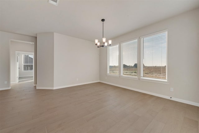 unfurnished room with light hardwood / wood-style floors and an inviting chandelier