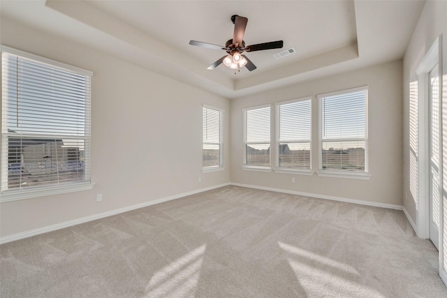 carpeted spare room featuring a raised ceiling and ceiling fan