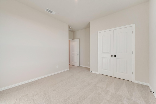 unfurnished bedroom with light colored carpet and a closet