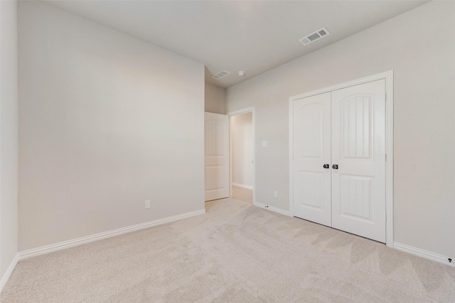 unfurnished bedroom with light carpet and a closet