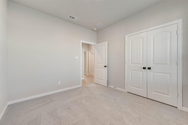 unfurnished bedroom featuring light colored carpet and a closet