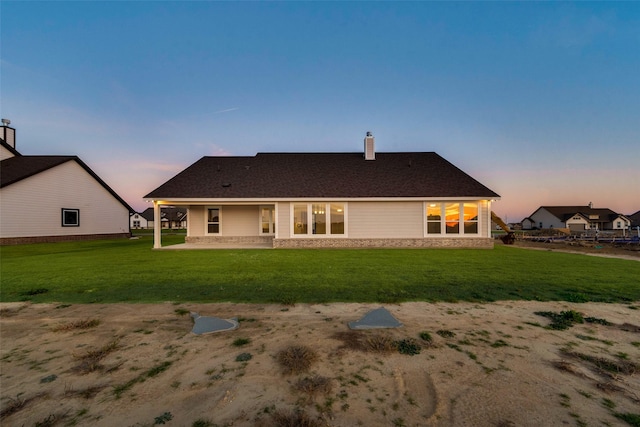 back house at dusk featuring a yard