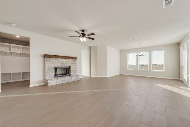 unfurnished living room with a stone fireplace, light hardwood / wood-style floors, and ceiling fan with notable chandelier