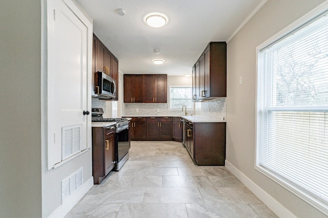 kitchen featuring sink, light tile floors, gas range, tasteful backsplash, and dark brown cabinetry