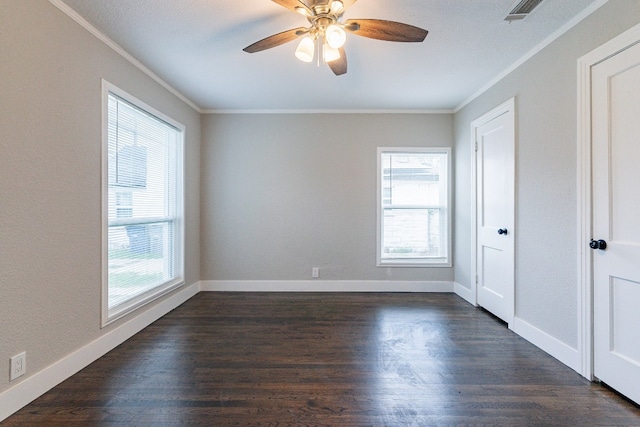 empty room with ceiling fan, crown molding, dark wood-type flooring, and a wealth of natural light