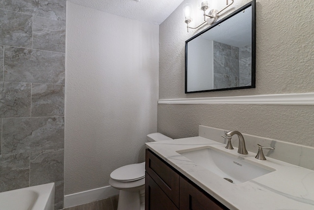 bathroom featuring toilet, vanity with extensive cabinet space, and a textured ceiling