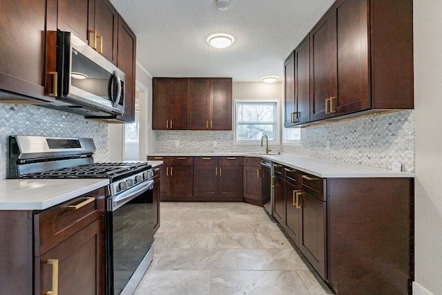 kitchen with appliances with stainless steel finishes, dark brown cabinets, backsplash, sink, and light tile flooring