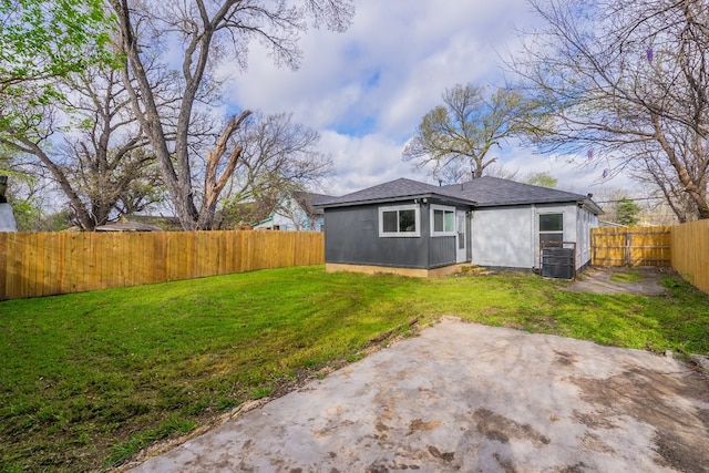 rear view of house with central AC, a lawn, and a patio area