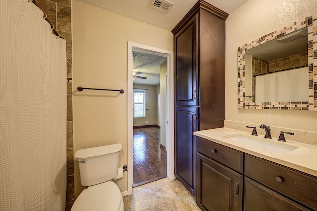 bathroom featuring vanity, a textured ceiling, ceiling fan, wood-type flooring, and toilet