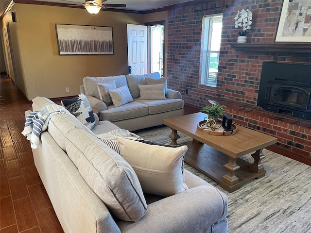 living room with a wood stove, ceiling fan, brick wall, crown molding, and hardwood / wood-style floors