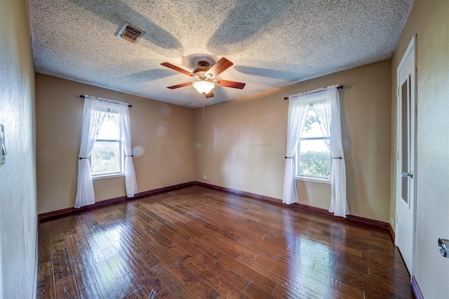 spare room featuring a textured ceiling, ceiling fan, wood finished floors, and visible vents