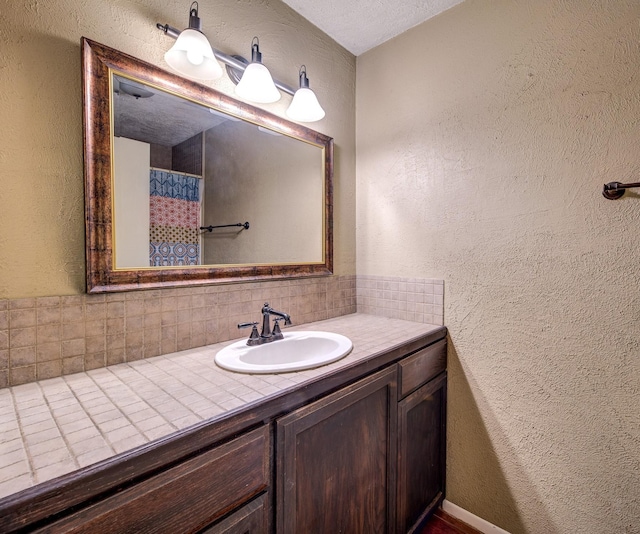 bathroom with a textured wall, vanity, and decorative backsplash