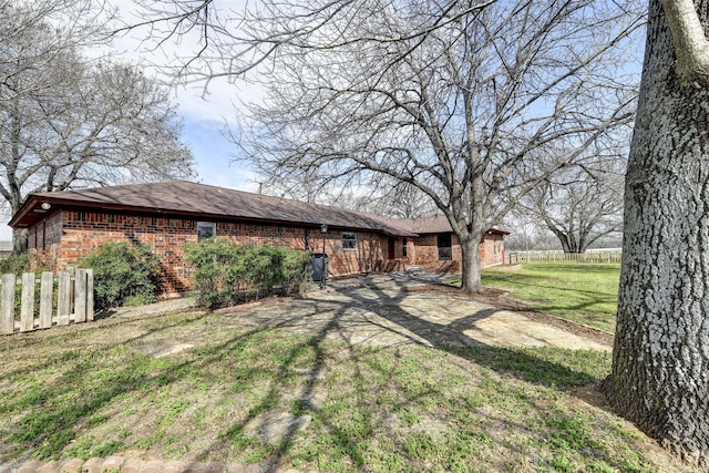 exterior space featuring brick siding, fence, and a lawn