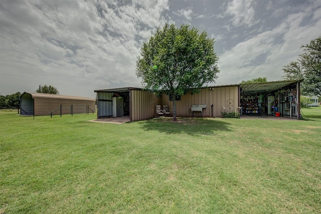 view of yard with fence, a pole building, and an outbuilding