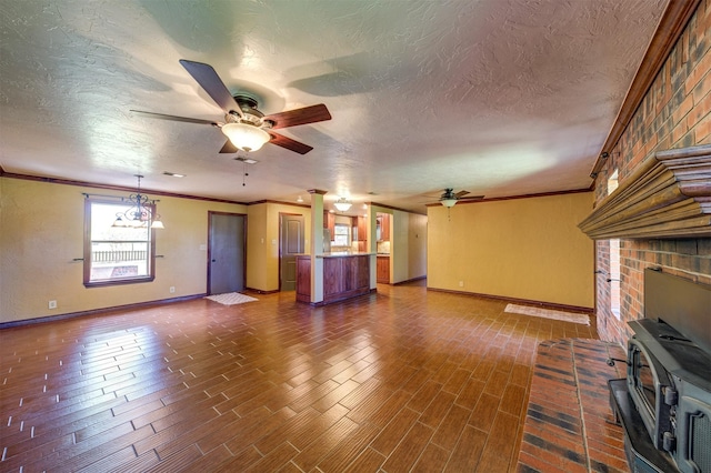 unfurnished living room with a textured ceiling, ceiling fan, crown molding, and baseboards