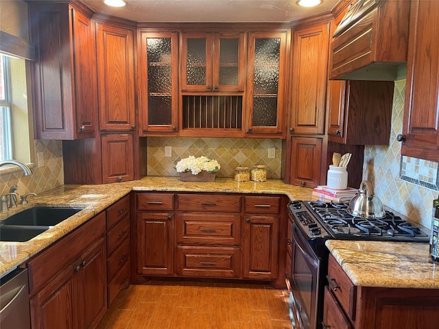 kitchen featuring light stone countertops, a sink, glass insert cabinets, backsplash, and appliances with stainless steel finishes