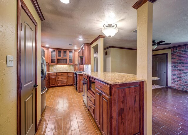 dining area with a wood stove, crown molding, brick wall, and ceiling fan with notable chandelier