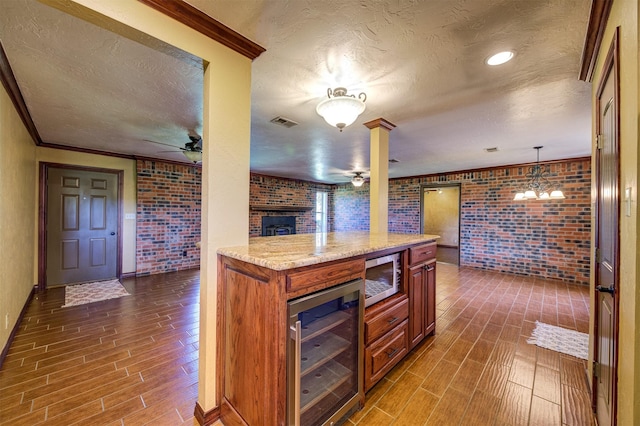 bar with stainless steel microwave, dark wood-style flooring, brick wall, ceiling fan, and beverage cooler