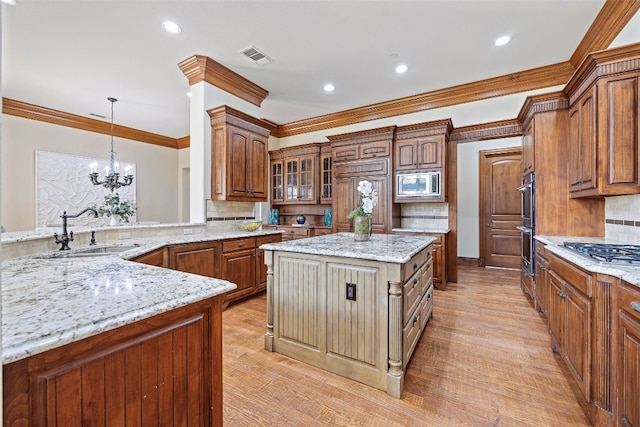 kitchen featuring sink, built in appliances, decorative light fixtures, a kitchen island, and light stone countertops