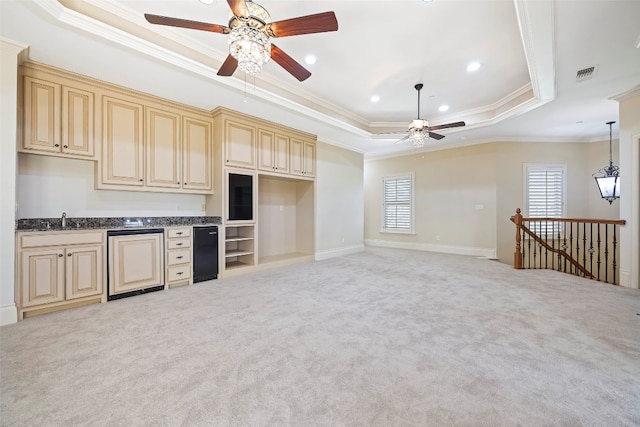 kitchen featuring ornamental molding, a tray ceiling, sink, and light carpet