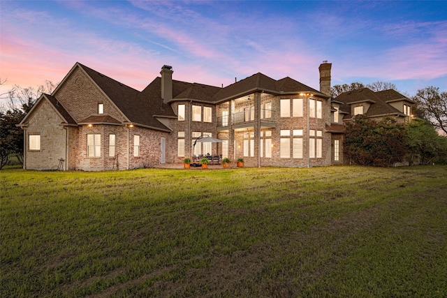 back house at dusk featuring a lawn