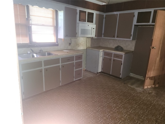 kitchen featuring white cabinetry, tasteful backsplash, sink, and dark tile flooring