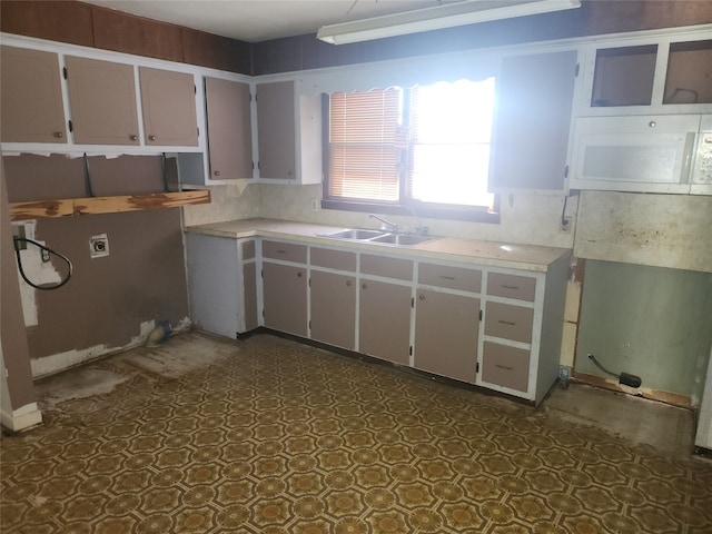 kitchen with tasteful backsplash, sink, and dark tile flooring