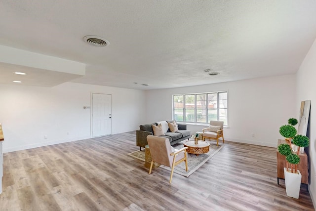 living room with a textured ceiling and light wood-type flooring