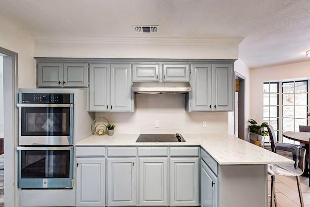 kitchen featuring double oven, a textured ceiling, gray cabinets, black electric stovetop, and backsplash