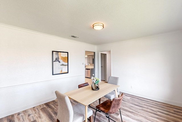 dining room with dark hardwood / wood-style flooring, a textured ceiling, and crown molding