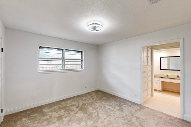 spare room with light carpet and a textured ceiling