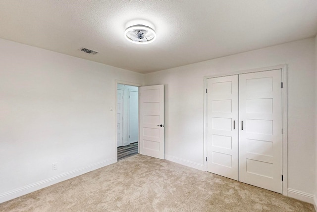 unfurnished bedroom with a closet and light carpet