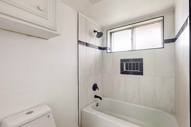 bathroom with tiled shower / bath combo, toilet, and a textured ceiling