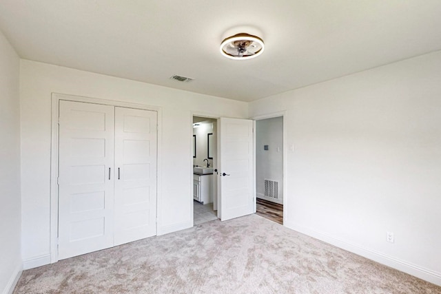 unfurnished bedroom with sink, light colored carpet, and a closet