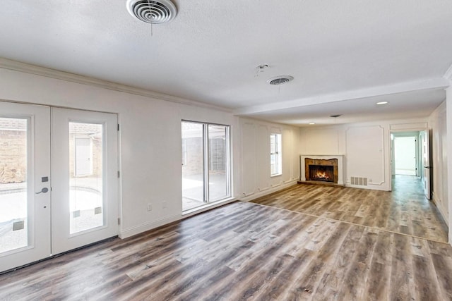 unfurnished living room featuring hardwood / wood-style floors, plenty of natural light, and french doors