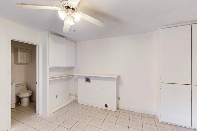 clothes washing area with ceiling fan and light tile floors