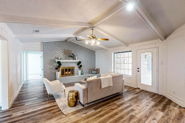 living room featuring vaulted ceiling with beams, ceiling fan, dark hardwood / wood-style floors, and a fireplace