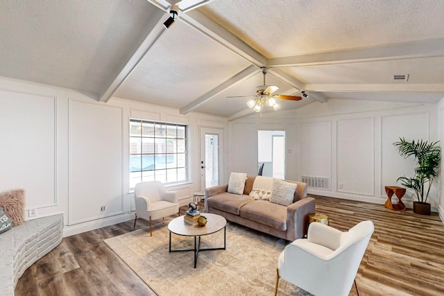 living room featuring a textured ceiling, wood-type flooring, ceiling fan, and lofted ceiling with beams