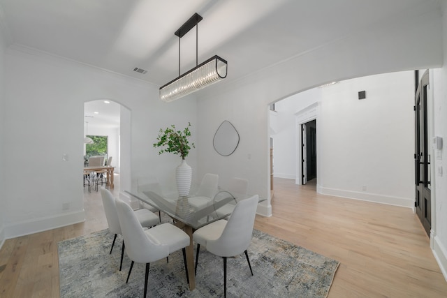 dining room with light hardwood / wood-style floors, crown molding, and a chandelier